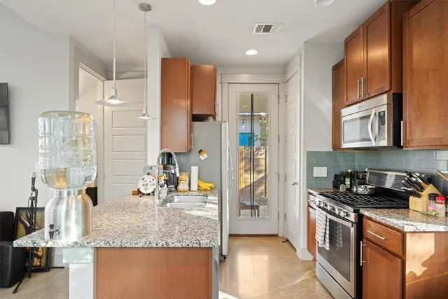a kitchen with stainless steel appliances granite countertop a refrigerator a stove and a sink