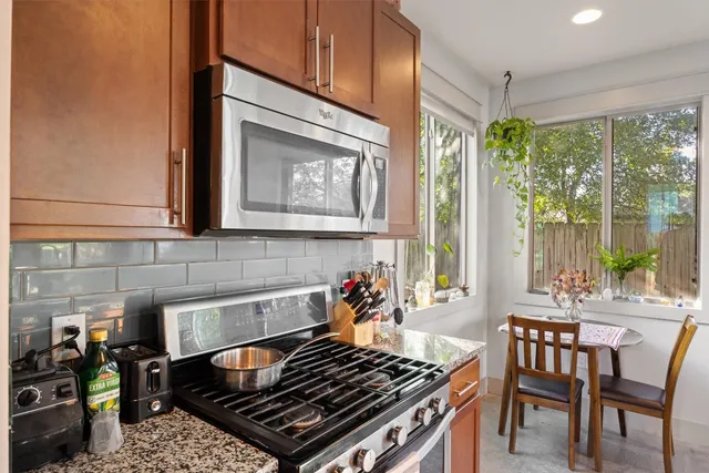 a kitchen with stainless steel appliances granite countertop a stove a sink and a dining table view