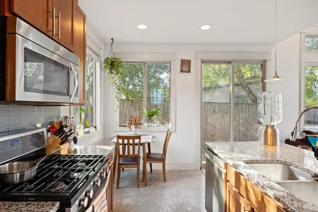 a kitchen with stainless steel appliances granite countertop a stove a sink and a dining table with granite countertops