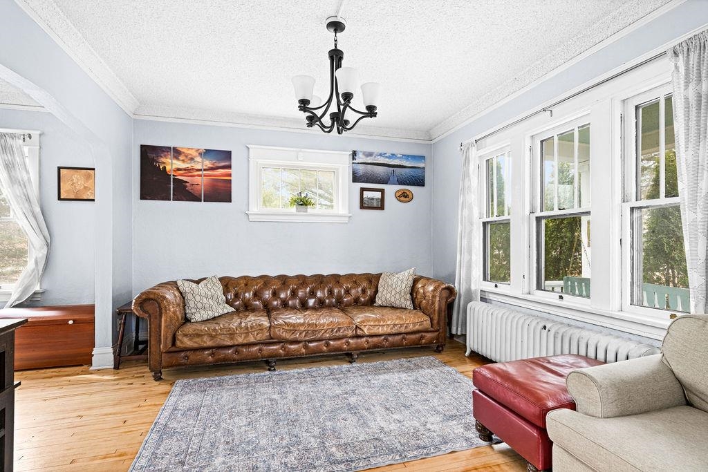 4608 Regent Street Duluth, MN 55804 - Photo 12 of 43 Living area with radiator, ornamental molding, an inviting chandelier, light wood-style floors, and a textured ceiling