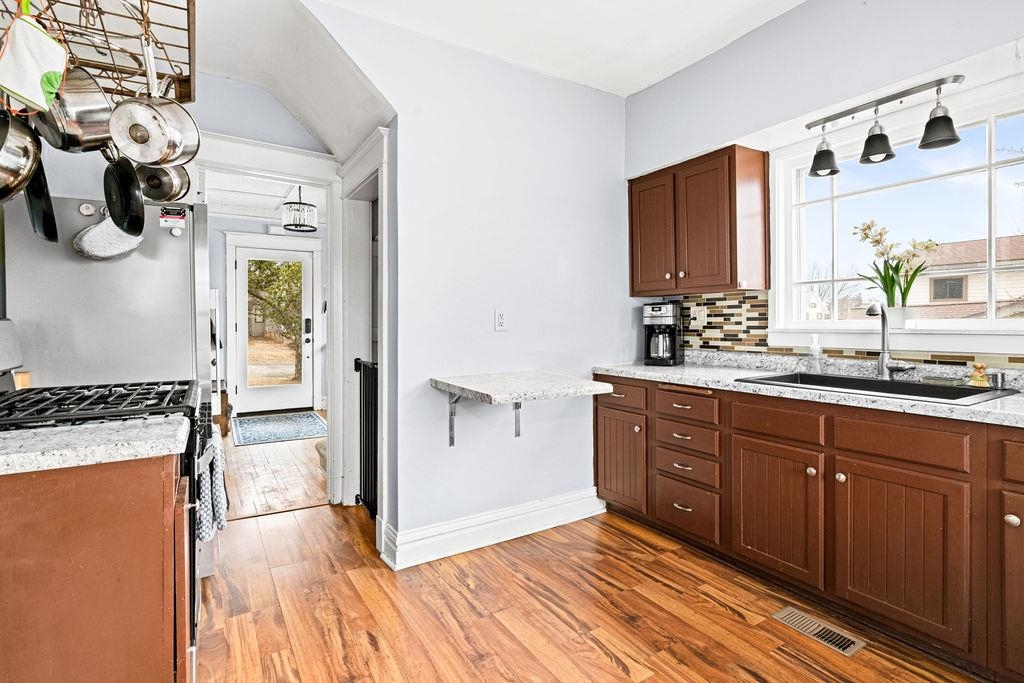 4608 Regent Street Duluth, MN 55804 - Photo 18 of 43 Kitchen with visible vents, light wood-style flooring, a sink, decorative backsplash, and stainless steel range with gas stovetop