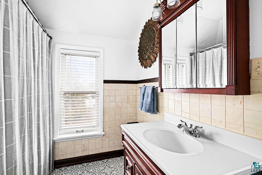 4608 Regent Street Duluth, MN 55804 - Photo 28 of 43 Bathroom with a wainscoted wall, a shower with curtain, tile walls, and vanity