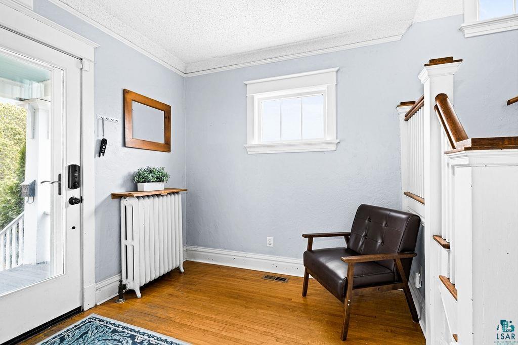 4608 Regent Street Duluth, MN 55804 - Photo 9 of 43 Living area with wood finished floors, baseboards, radiator heating unit, a textured ceiling, and crown molding