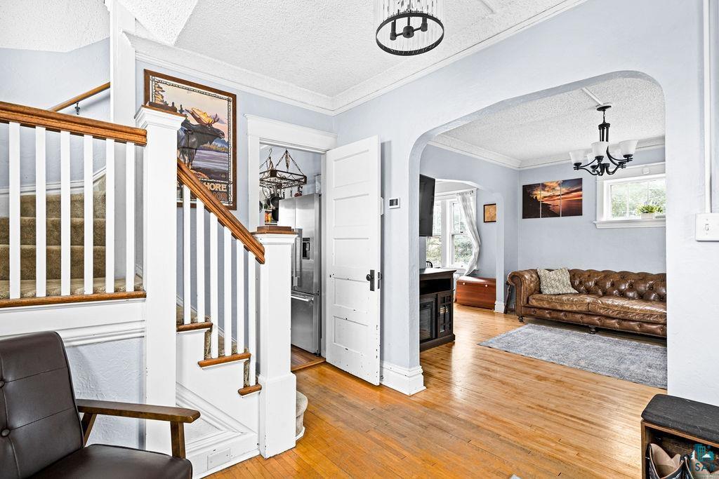 4608 Regent Street Duluth, MN 55804 - Photo 10 of 43 Foyer entrance featuring a notable chandelier, a textured ceiling, wood finished floors, stairway, and arched walkways
