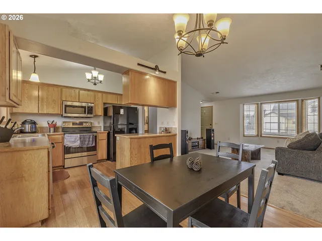 a kitchen with stainless steel appliances kitchen island granite countertop a table chairs sink and cabinets