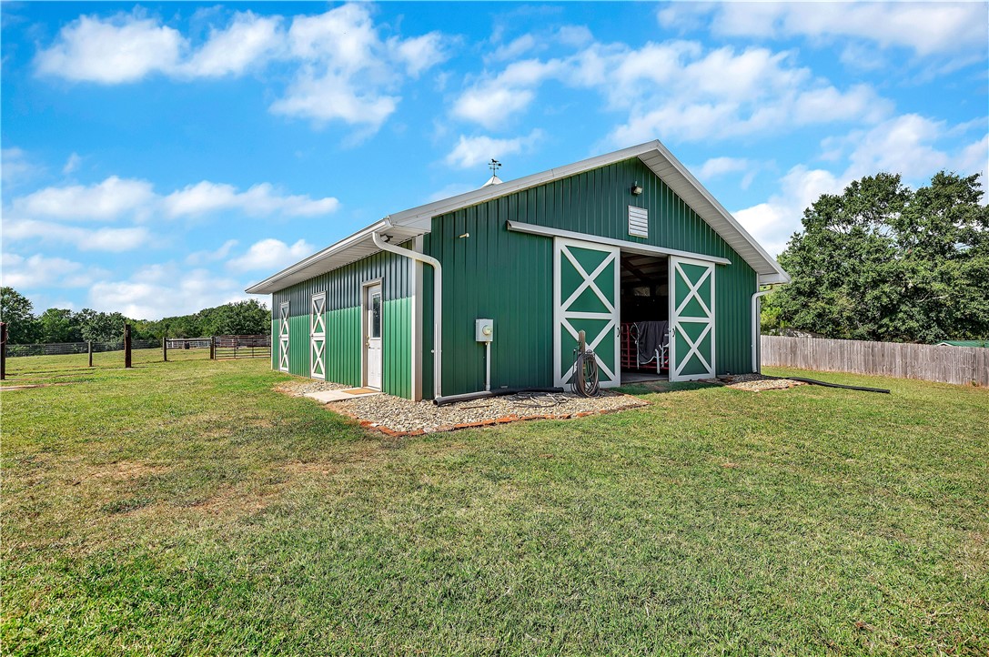 3620 Centerville Road Anderson, SC 29625 - Photo 10 of 49 Functional outbuilding with sliding double doors stands ready on an expansive grassy pasture.