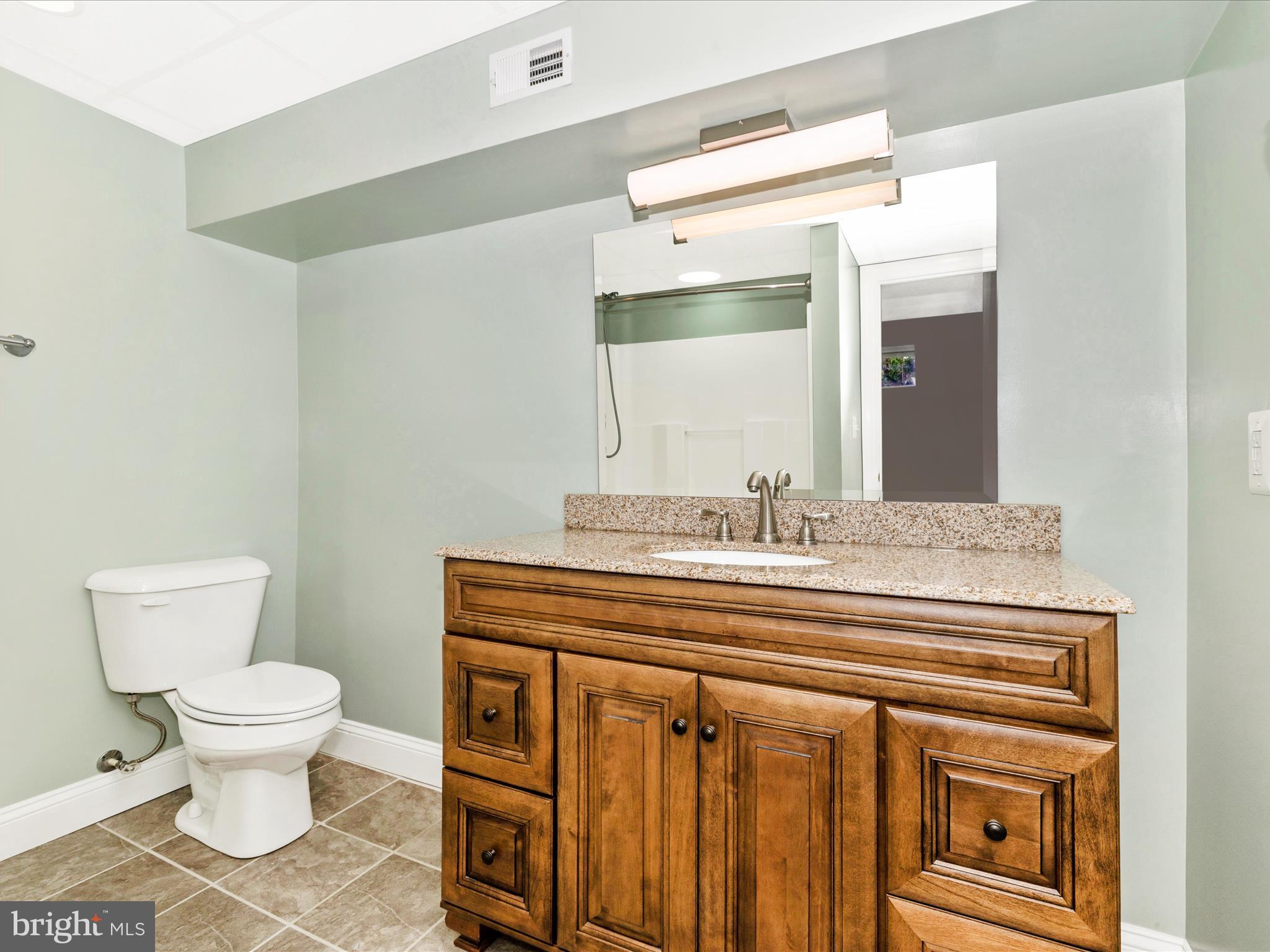8429 Woodville Road Mount Airy, MD 21771 - Photo 40 of 75 a bathroom with a granite countertop toilet a sink and a mirror