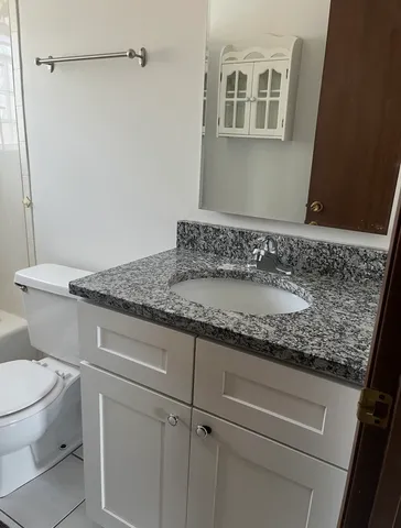 a bathroom with a granite countertop sink toilet and shower