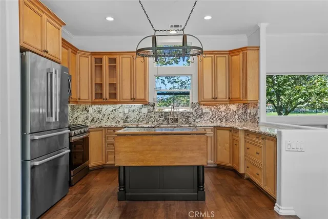 a kitchen with stainless steel appliances granite countertop a refrigerator a stove a sink and a microwave