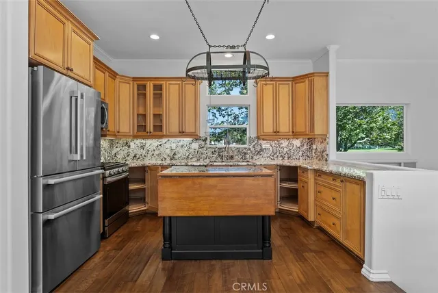 a kitchen with stainless steel appliances granite countertop a refrigerator a stove a sink dishwasher and a oven with wooden floor