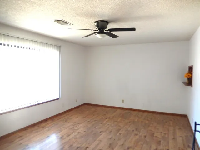 a view of an empty room with a ceiling fan and wooden floor