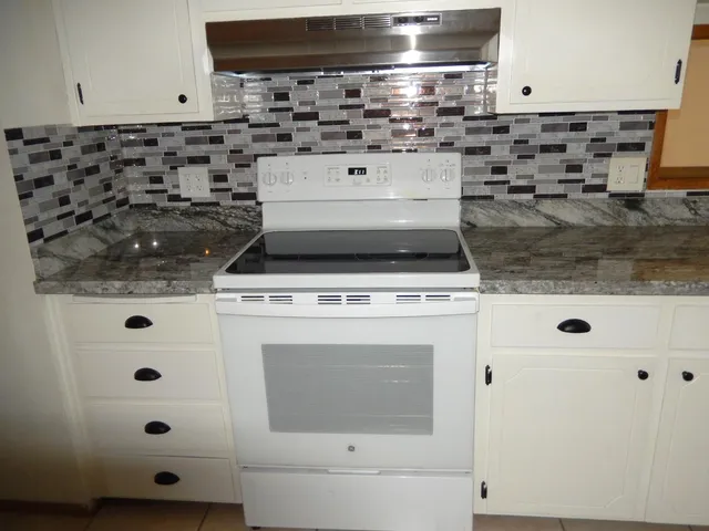 a kitchen with stainless steel appliances granite countertop a stove a sink and a refrigerator