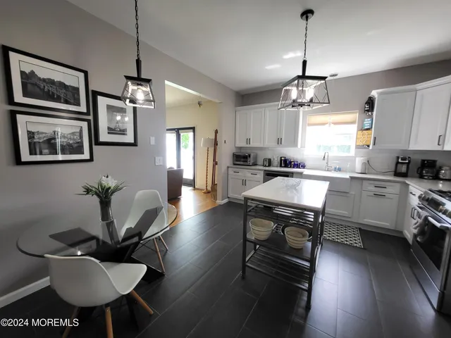 a kitchen with stainless steel appliances kitchen island granite countertop a stove a sink a dining table and chairs with wooden floor