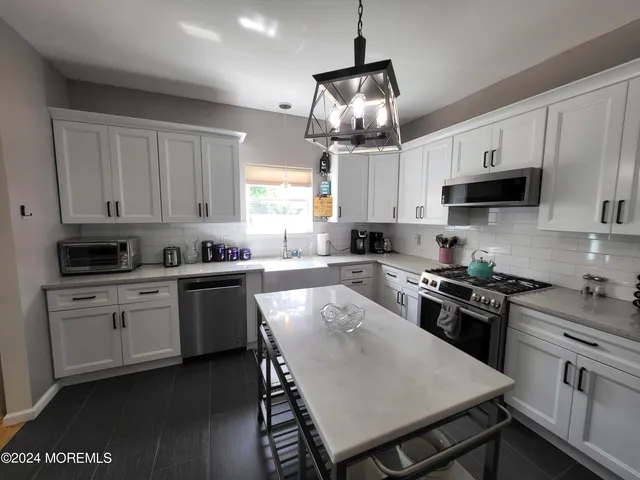 a kitchen with stainless steel appliances granite countertop a stove refrigerator a sink a microwave and cabinets