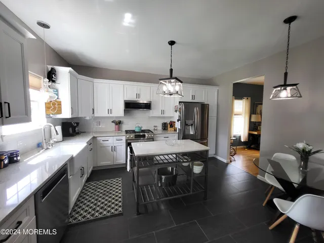 a kitchen with stainless steel appliances a dining table chairs stove a sink and a window