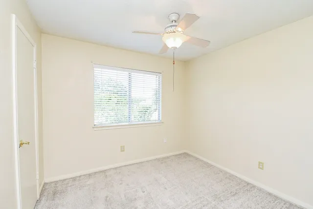 an empty room with a window and a chandelier fan