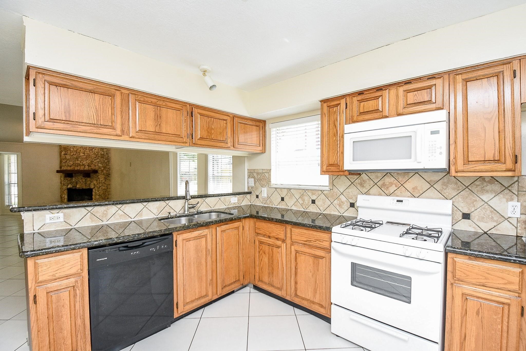 2623 Forestbrook Drive Spring, TX 77373 - Photo 9 of 27 a kitchen with granite countertop a sink stove and cabinets