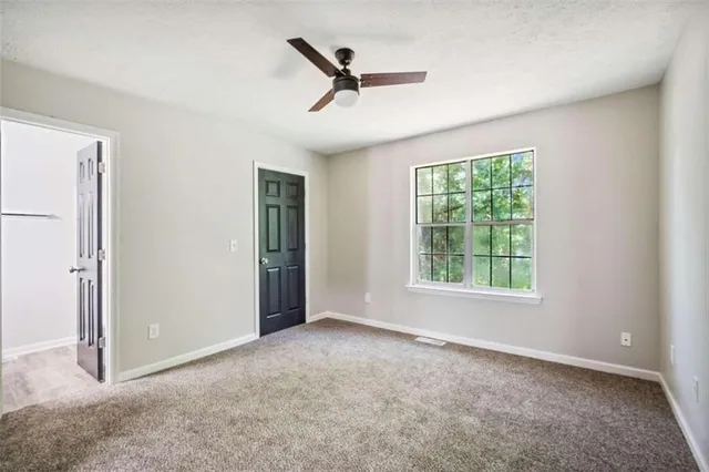 an empty room with ceiling fan and window