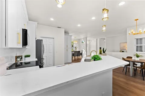 a kitchen with kitchen island a refrigerator a stove a dining table and chairs with wooden floor