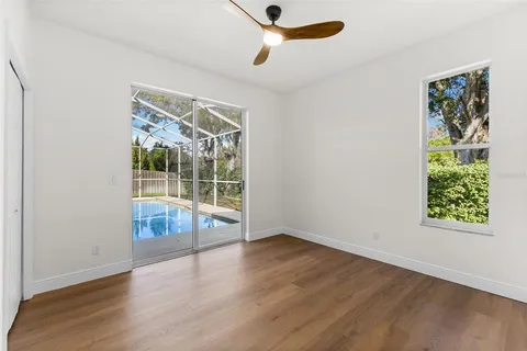 an empty room with wooden floor fan and windows