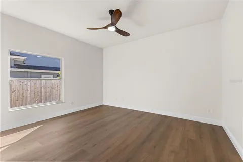 a view of an empty room with window and wooden floor