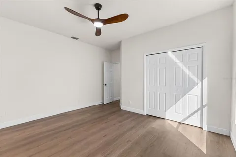 an empty room with wooden floor fan and windows