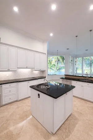 a kitchen with kitchen island granite countertop white cabinets and window