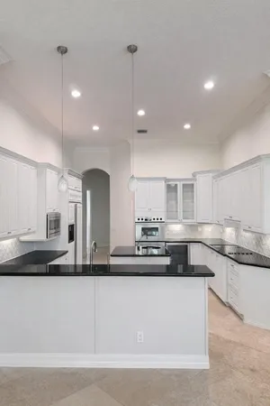a large kitchen with granite countertop a large counter top a sink stainless steel appliances and cabinets