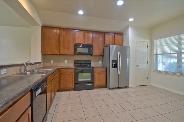 a kitchen with stainless steel appliances granite countertop a refrigerator sink and stove