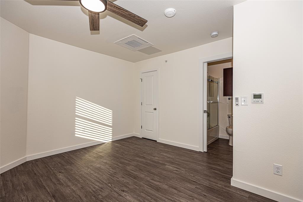 3022 Forest Lane, Unit 110 Dallas, TX 75234 - Photo 9 of 12 an empty room with wooden floor and windows