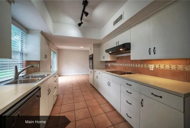 a large kitchen with granite countertop a sink a stove and cabinets