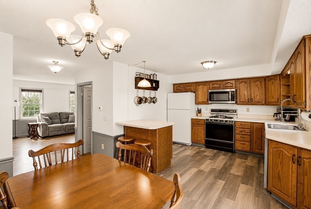53 Century Way, Unit 53 Gardner, MA 01440 - Photo 6 of 22 a large white kitchen with stainless steel appliances granite countertop a stove oven a sink dishwasher and white cabinets with wooden floor