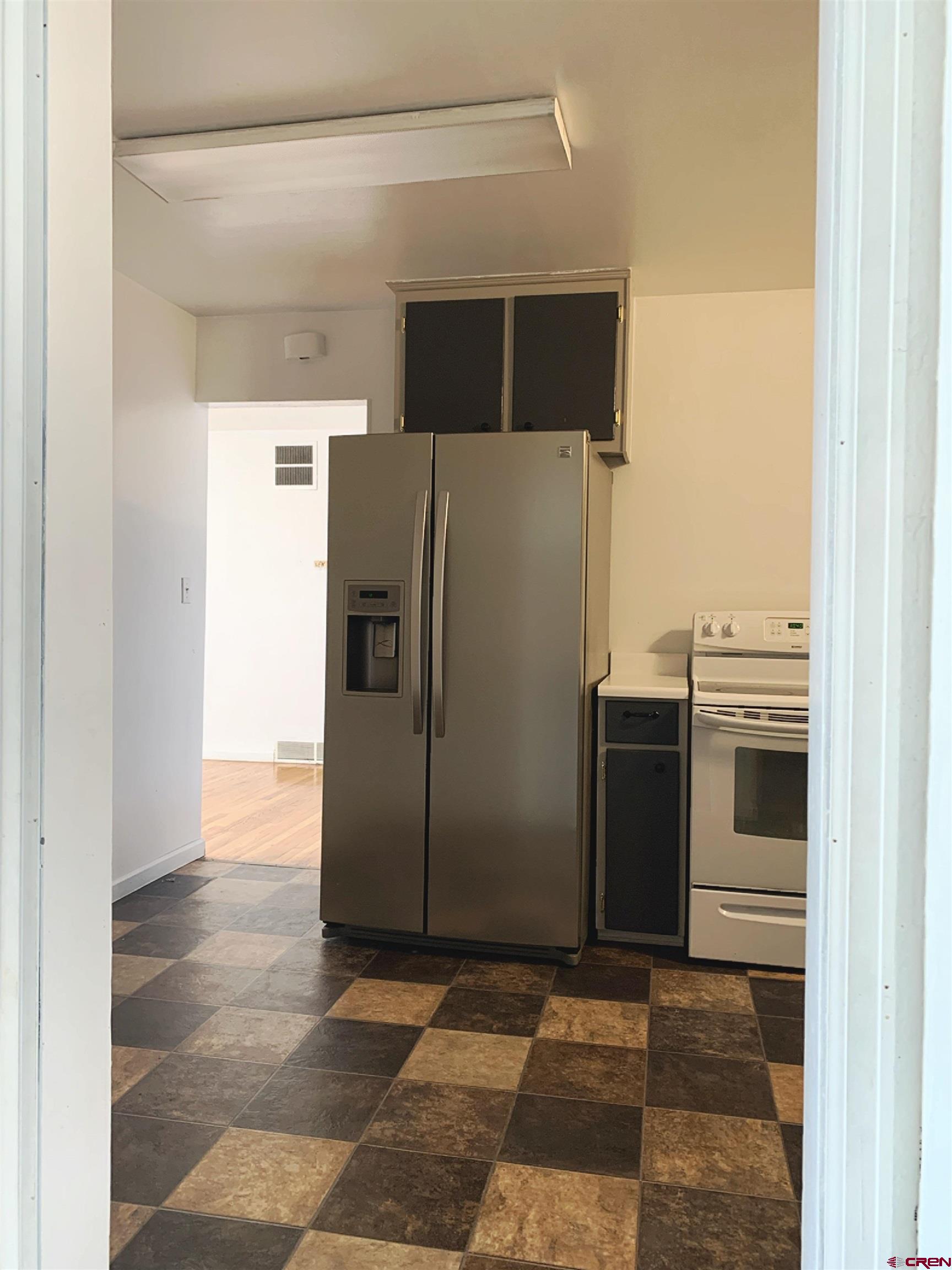 331 Morris Street Monte Vista, CO 81144 - Photo 13 of 31 a view of a refrigerator in kitchen and an empty room
