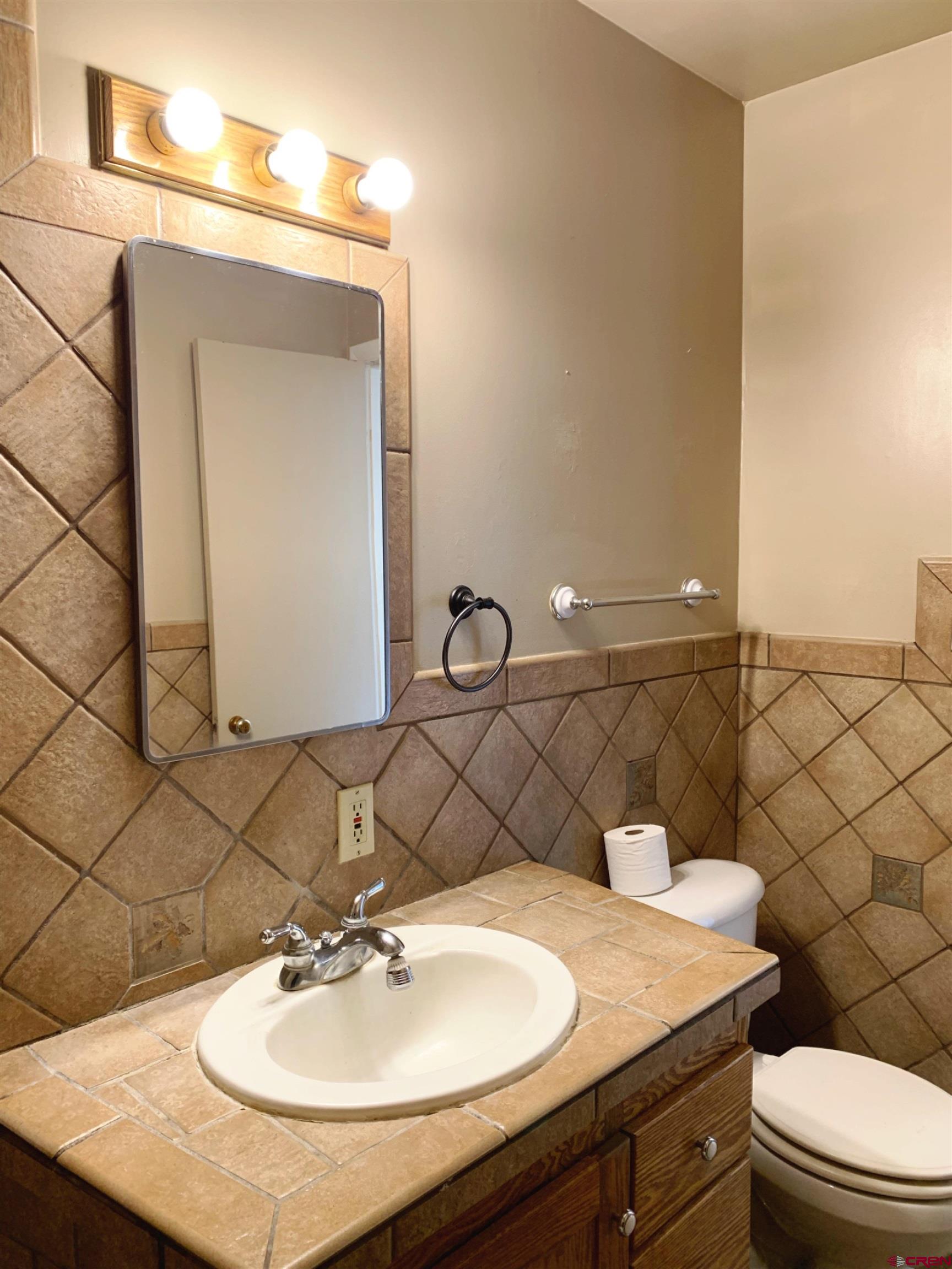 331 Morris Street Monte Vista, CO 81144 - Photo 15 of 31 a bathroom with a sink a toilet and mirror