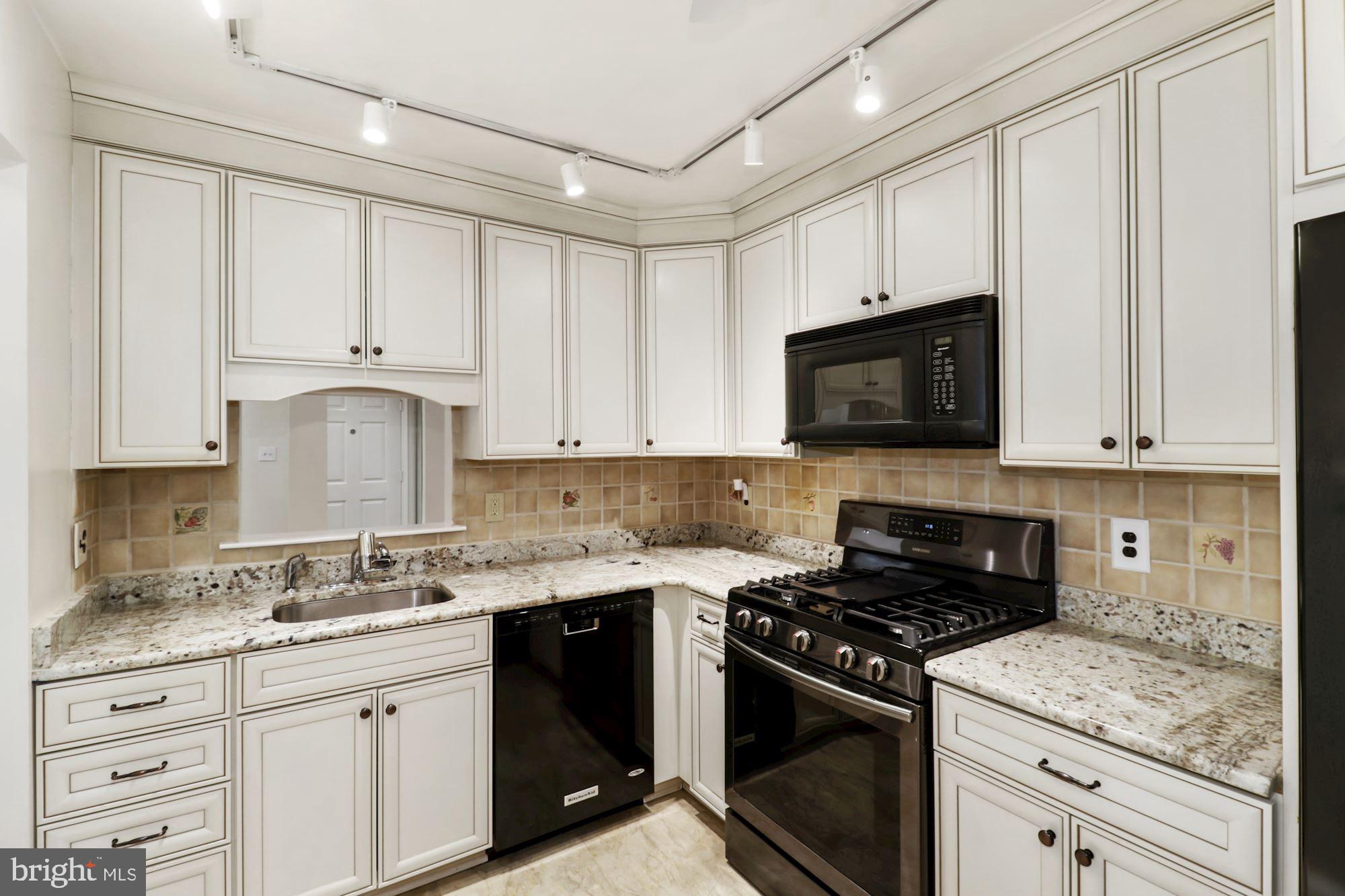 a kitchen with granite countertop white cabinets and black appliances
