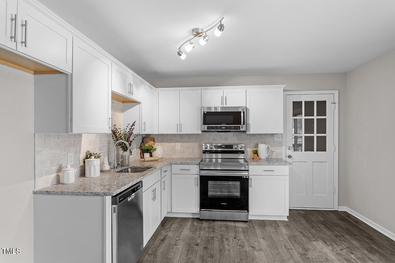 5137 Shield Circle Raleigh, NC 27603 - Photo 6 of 36 a kitchen with stainless steel appliances a sink stove oven and white cabinets