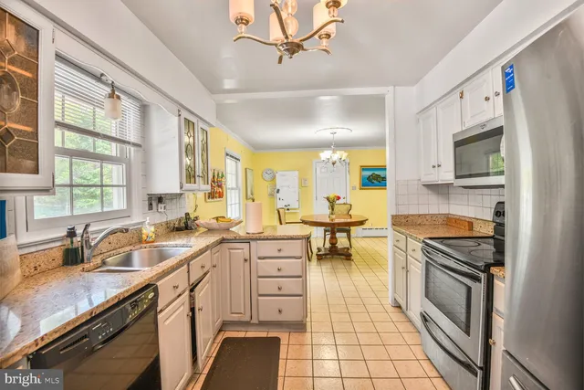 a kitchen with granite countertop a sink a counter space appliances and cabinets