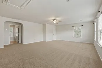 a view of an empty room with chandelier fan and windows