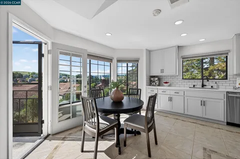 a kitchen with stainless steel appliances granite countertop a table and chairs in it