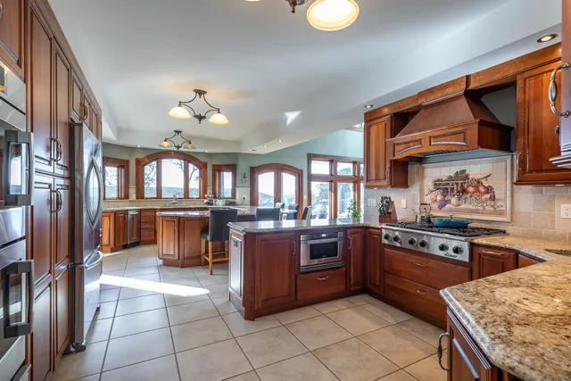 a kitchen with stainless steel appliances granite countertop a stove top oven a sink dishwasher and cabinets with wooden floor