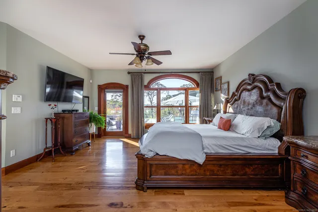 a bedroom with a large bed a flat tv screen and dresser