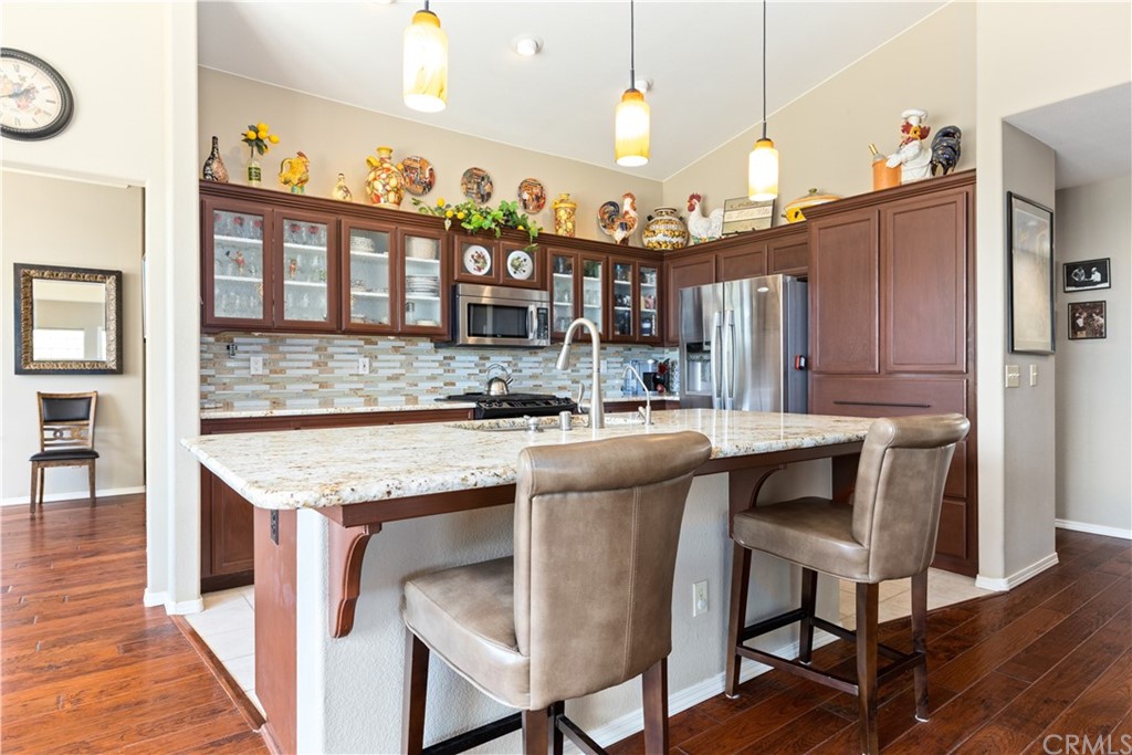 1612 Via Flora Paso Robles, CA 93446 - Photo 7 of 35 a open kitchen with granite countertop a table chairs stove and a wooden floor