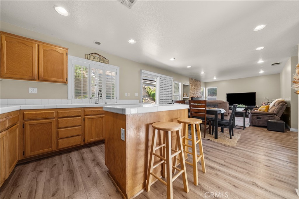 27687 Ron Ridge Drive Saugus, CA 91350 - Photo 7 of 50 a kitchen with stainless steel appliances kitchen island granite countertop a stove top oven a sink a dining table and chairs with wooden floor