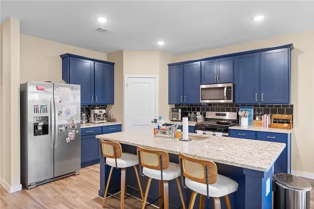a kitchen with granite countertop a refrigerator stove microwave and cabinets