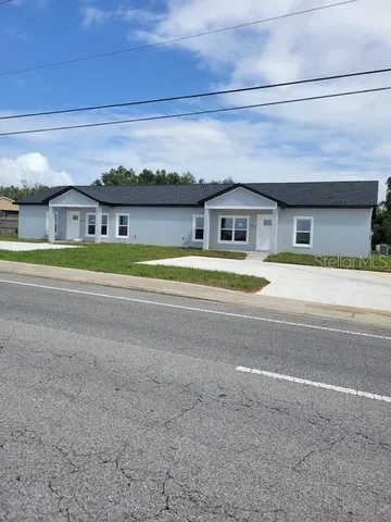 a front view of a house with a yard and trees in the background