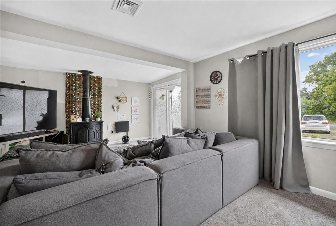 3123 Orefield Road Allentown, PA 18104 - Photo 29 of 39 A well-lit family room showcases a cozy wood-burning stove and plush carpeting, perfect for relaxation.