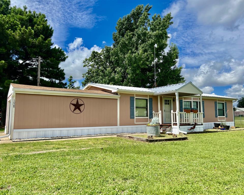 Manufactured / mobile home with a porch, a front yard, and a metal roof