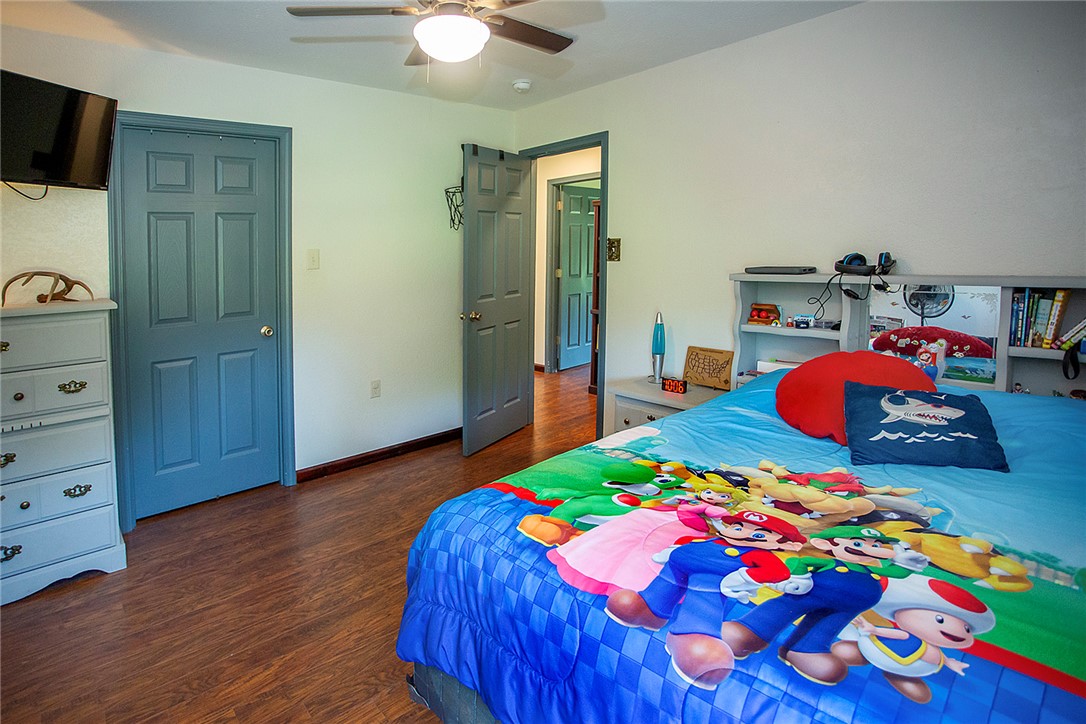 3726 St Joe Road Atkins, AR 72823 - Photo 20 of 41 Bedroom featuring wood-finish flooring, a ceiling fan with integrated lighting, and multiple paneled doors