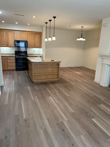 a kitchen with stainless steel appliances kitchen island wooden floors wooden cabinets and entryway