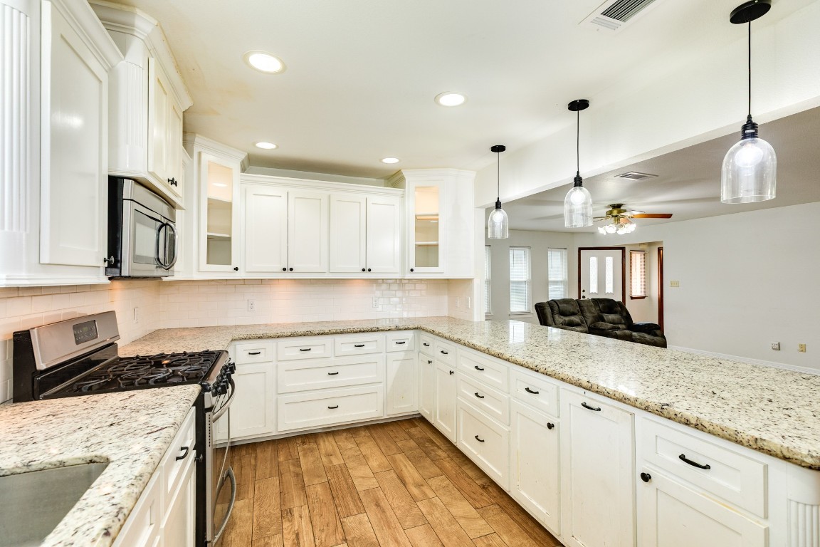 a kitchen with granite countertop a stove a sink a center island and wooden floor